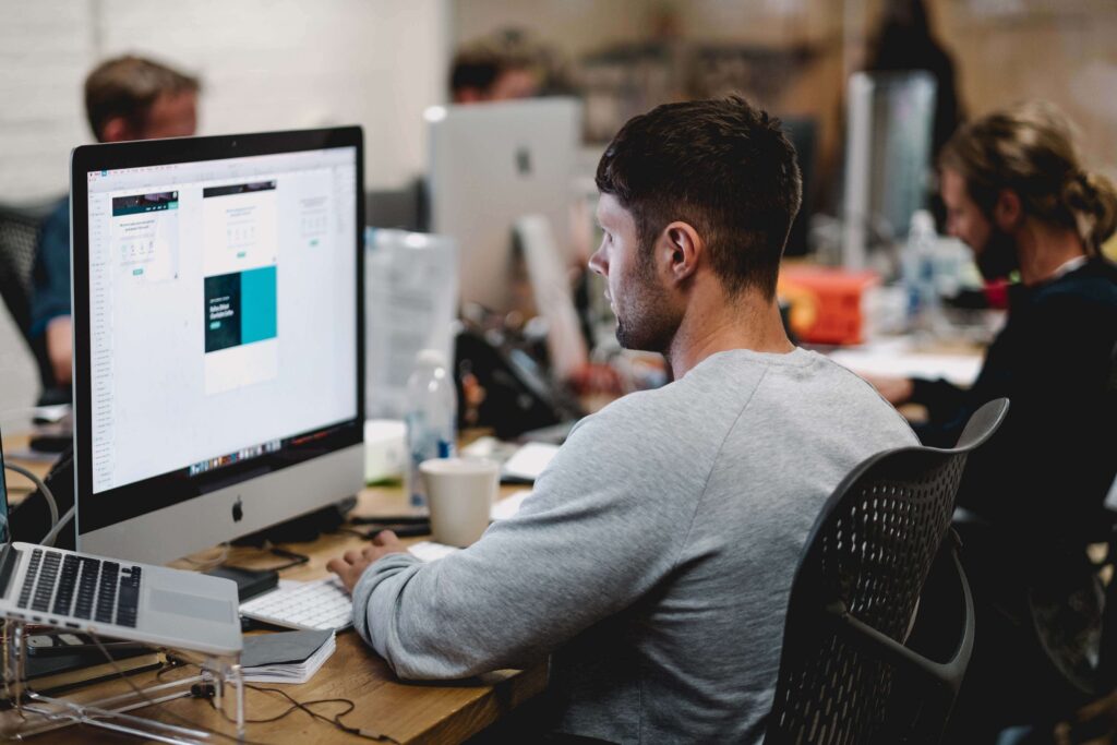 Man on imac, working in office, clean desk, technology, man looking at computer monitor